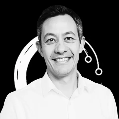 Fabian Zentel im weißen Hemd, lächelnd vor schwarzem Hintergrund